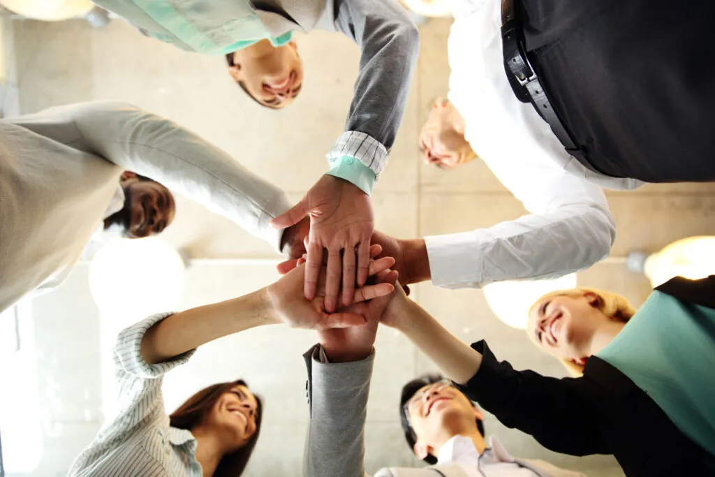 Diverse business team placing their hands together in a teamwork gesture